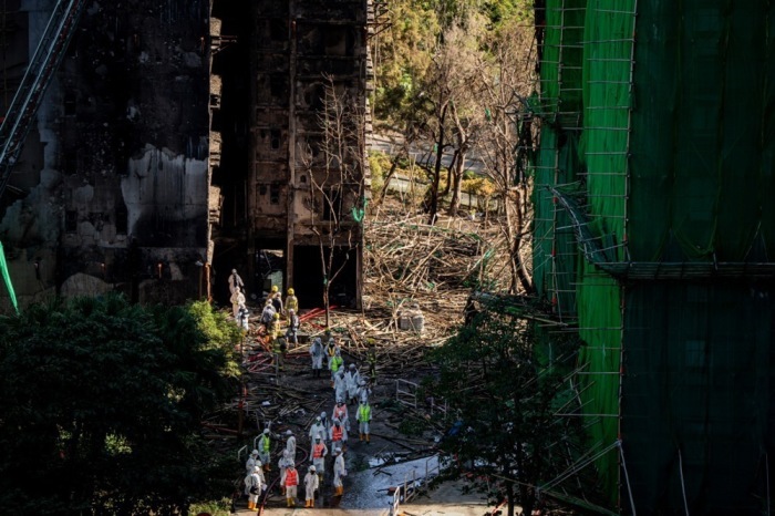 Feuerwehrleute und Mitarbeiter der Disaster Victim Identification (DVI)-Einheit verlassen einen vom Feuer zerstörten Turm im Wohnviertel Wang Fuk Court in Hongkong. Foto: epa/Leung Man Hei