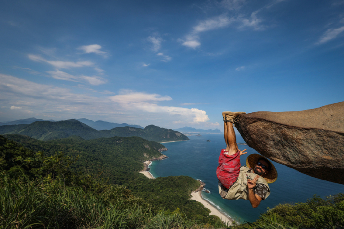 Bernardo hängt für ein Bild an dem Felsen «Pedra do Telegrafo» mit dem Meer im Hintergrund. Touristen und Einheimische lassen sich hier an der Spitze des Felsens in scheinbar waghalsigen Posen ablichten. Foto: Aline Massuca/dpa