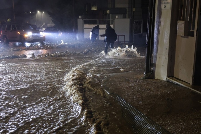 Eine Person geht über eine überflutete Straße im Sturm in Glyfada nahe Athen. Unwetter bringen Starkregen und Orkanböen. Foto: EPA/George Vitsaras