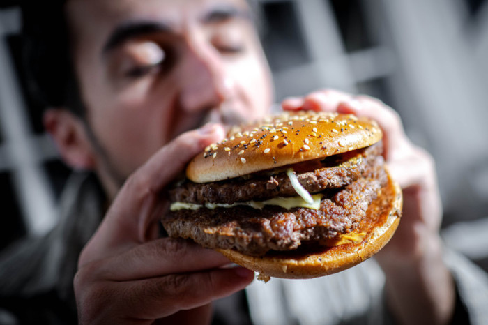 Ein Mann beißt in einen Burger. Foto: Sina Schuldt/dpa