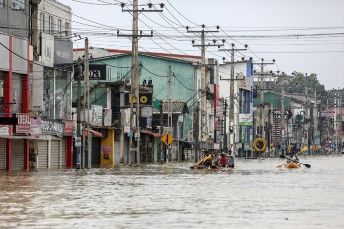 Menschen waten nach heftigen Regenfällen durch eine überflutete Straße bei Colombo, zahlreiche Regionen stehen weiter unter Wasser. Foto: EPA/Chamila Karunarathne