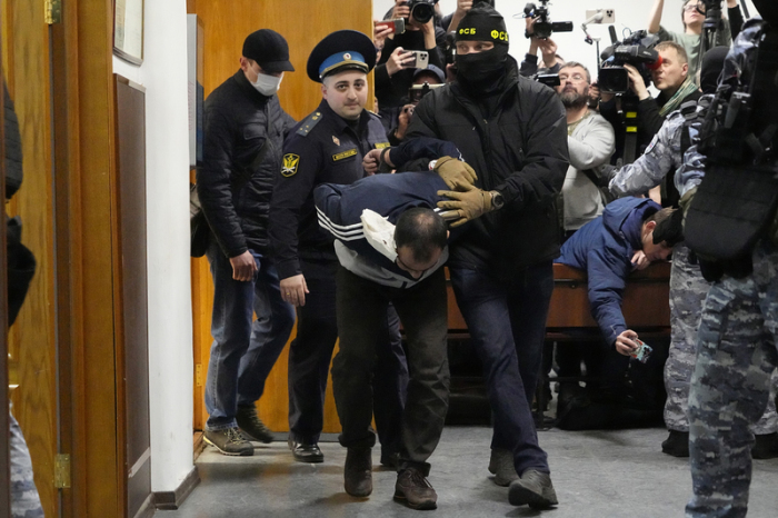 Ein Tatverdächtiger des Terroranschlags auf die Konzerthalle Crocus City Hall wird von Polizisten und FSB-Beamten im Basmanny-Bezirksgericht eskortiert. Foto: Alexander Zemlianichenko/Ap/dpa