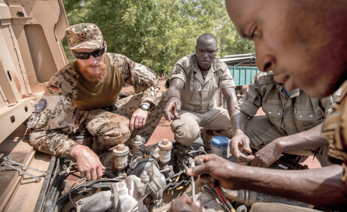 Ein deutscher Soldat erklärt einem malischen Soldaten die Reparatur eines LKWs. Foto: epa/Michael Kappeler