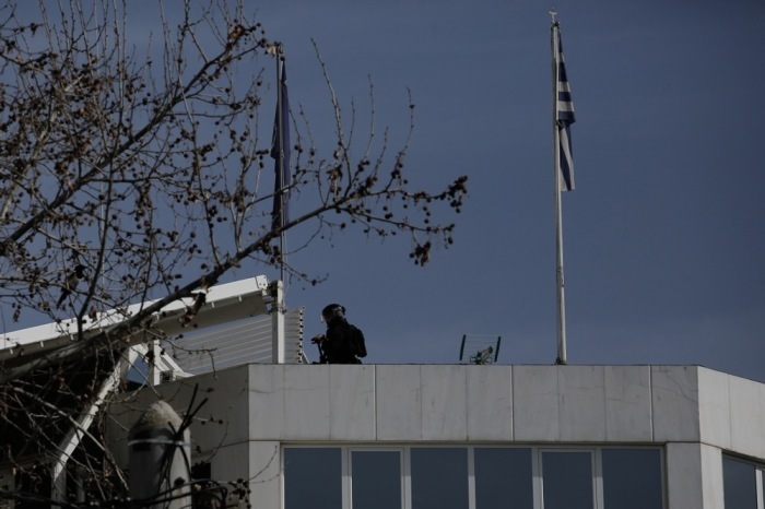 Ein Beamter einer Spezialeinheit geht auf dem Dach eines Gebäudes einer Reederei in Glyfada spazieren. Foto: epa/Kostas Tsironis