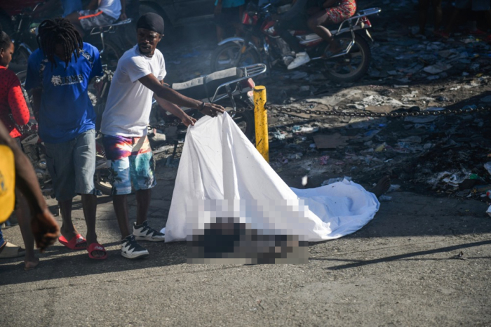 In einer Straße in Port-au-Prince deckt ein Mann den Körper einer Person auf dem Boden zu. Foto: epa/Johnson Sabin
