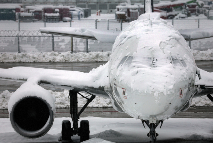 Ein verschneites Flugzeug steht am Flughafen. Die Sperrung des Flugbetriebes am Münchner Flughafen ist wegen starker Schneefälle bis 03.12.2023 um 6.00 Uhr verlängert worden. Foto: Karl-Josef Hildenbrand/dpa