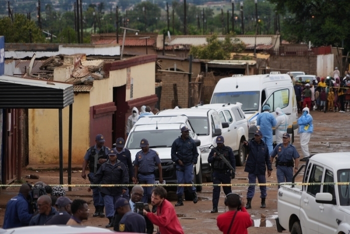 Schaulustige versammeln sich am Ort des Vorfalls, bei dem Bewaffnete in einer Kneipe in Bekkersdal mindestens neun Menschen töteten und mindestens zehn verletzten. Foto: Alfonso Nqunjana/Ap/dpa