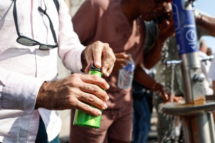 Menschen kühlen sich während einer Hitzewelle an einem Trinkbrunnen in Paris ab. Frankreich erlebt landesweit hohe Temperaturen. Foto: EPA/Mohammed Badra