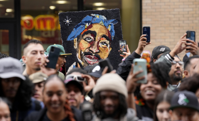 Fans halten ein Bild des verstorbenen Rappers Tupac Shakur, während einer Zeremonie, bei der Shakur mit einem Stern auf dem Hollywood Walk of Fame geehrt wird. Foto: Chris Pizzello/Invision/ap/dpa