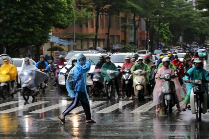 Menschen auf Motorrädern warten im Regen an einer Ampel in Hanoi nach dem Durchzug des Taifuns Bualoi. Foto: epa/Luong Thai Linh