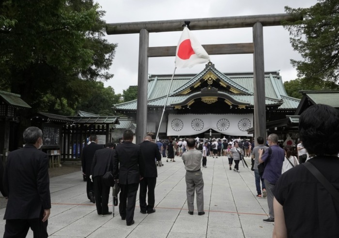 Besucher besuchen den Yasukuni-Schrein mit einer japanischen Nationalflagge, um für die Opfer des Zweiten Weltkriegs in Tokio zu beten. Foto: epa/Kimimasa Mayama