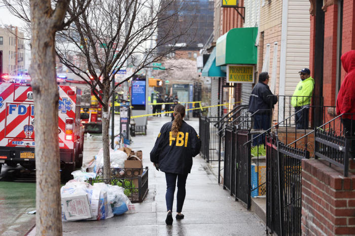 Ein FBI-Mitarbeiter läuft inmitten eines massiven Polizeieinsatzes am Tatort einer gemeldeten Schießerei in einer New Yorker U-Bahn den Bürgersteig entlang. Foto: epa/Justin Lane