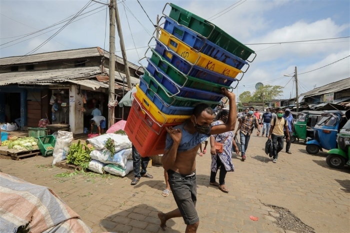 Ein mit einem Mundschutz versehener Arbeiter trägt leere Kartons auf einem öffentlichen Markt in Colombo. Foto: epa/Chamila Karunarathne