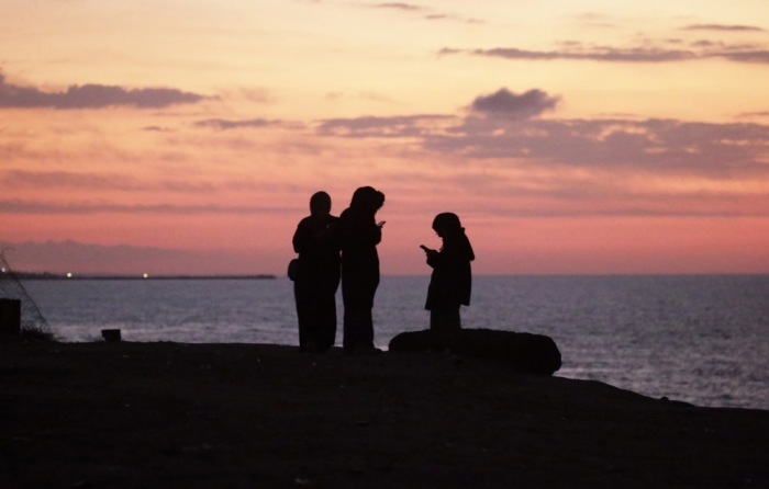 Bei Sonnenuntergang prüfen Palästinenser westlich des zentralen Gazastreifens den Internetempfang auf ihren Handys. Foto: epa/Rmohammed Saber
