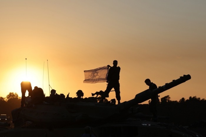 An der Grenze zum Gazastreifen hält ein israelischer Soldat während eines vorübergehenden Waffenstillstands eine israelische Flagge auf einem Panzer. Foto: epa/Abir Sultan