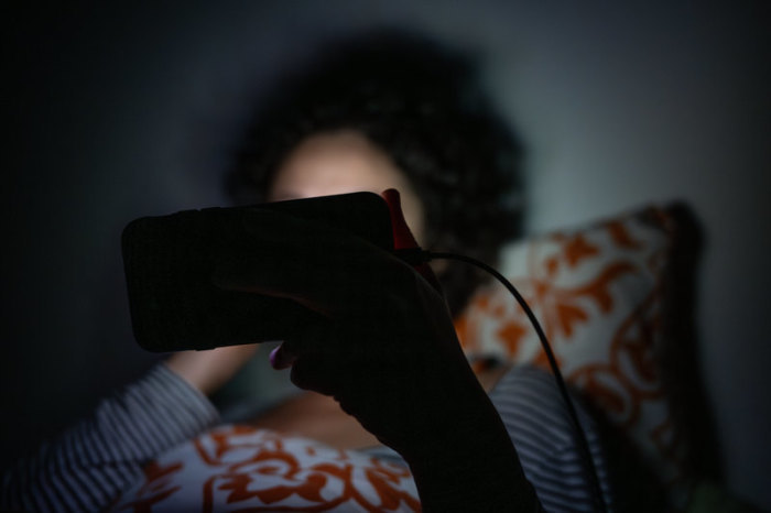 Eine Frau schaut im Bett eine Sendung auf dem Smartphone. Foto: Sebastian Gollnow/dpa/dpa-tmn