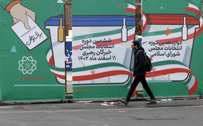 Ein Mann geht in einer Straße in Teheran neben dem Wahlplakat für die bevorstehenden Parlamentswahlen spazieren. Foto: epa/Abedin Taherkenareh