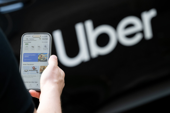 Ein Nutzer öffnet die Uber-App vor einem Mietwagen des Fahrdienstvermittlers in Berlin. Foto: Sebastian Gollnow/dpa