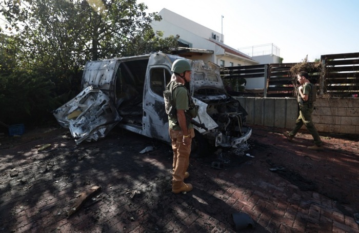 Die bewaffneten Ersthelfer prüfen den Schaden an einem Fahrzeug, das von einer Rakete getroffen wurde. Foto: epa/Atef Safadi