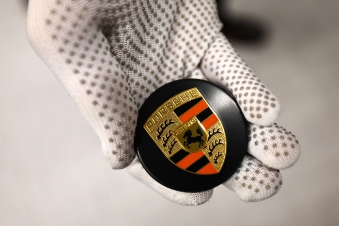 Ein Mitarbeiter hält in der Porsche Exclusive Manufaktur in Stuttgart eine Radnabenabdeckung für einen Porsche-Sportwagen. Foto: epa/Anna Szilagyi