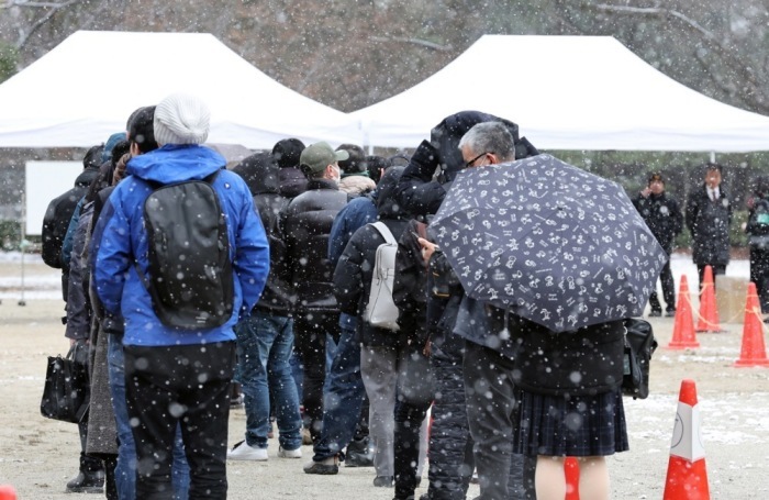 Die Menschen stehen bei Schneefall an, um vor der Urteilsverkündung im Fall der Brandstiftung und des Mordes bei der Kyoto-Animation in Kyoto Eintrittskarten zu erhalten. Foto: epa/Jiji Press Japan