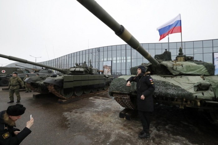 Ein Seekadett posiert vor einem russischen Panzerfahrzeug. Foto: epa/Anatoly Maltsev