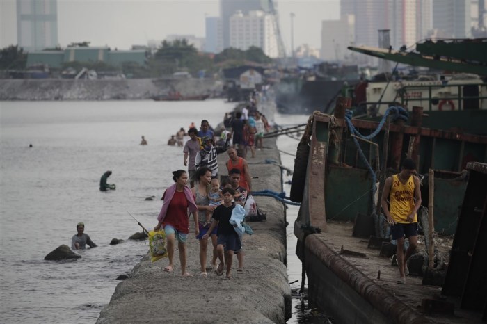 Philippinos manövrieren auf einem Wellenbrecher, um anlässlich des Schwarzen Samstags in der Bucht von Manila zu schwimmen. Foto: epa/Francis R. Malasig