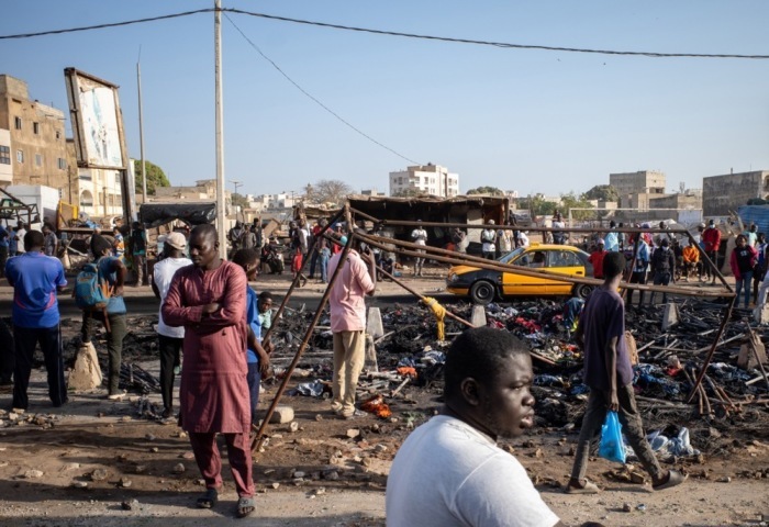Bewohner betrachten die verkohlten Überreste von Marktständen, die während der Proteste am Vortag in Dakar abgefackelt wurden. Foto: epa/Jerome Favre