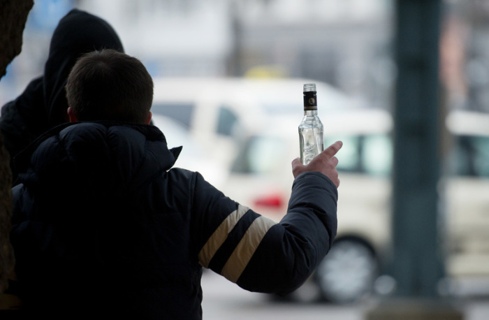 Ein stark alkoholisierter Mann gestikuliert am Hauptbahnhof in Hamburg mit einer Wodkaflasche in der Hand. Foto: Daniel Reinhardt/dpa