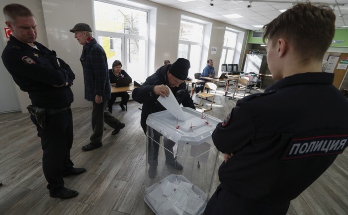Russische Polizisten bewachen eine Wahlurne, während ein älterer Mann während der Präsidentschaftswahlen in Moskau seine Stimme abgibt. Foto: EPA-EFE/Maxim Shipenkov