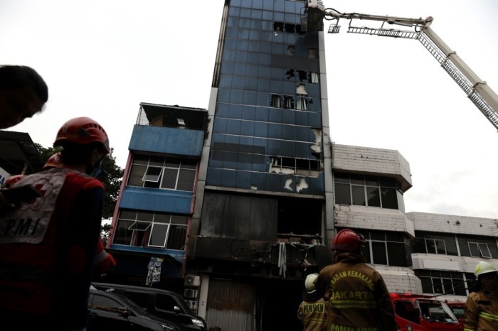 Feuerwehrleute und Rettungskräfte versammeln sich nach einem Brand in Jakarta vor einem Gebäude. Foto: epa/Mast Irham