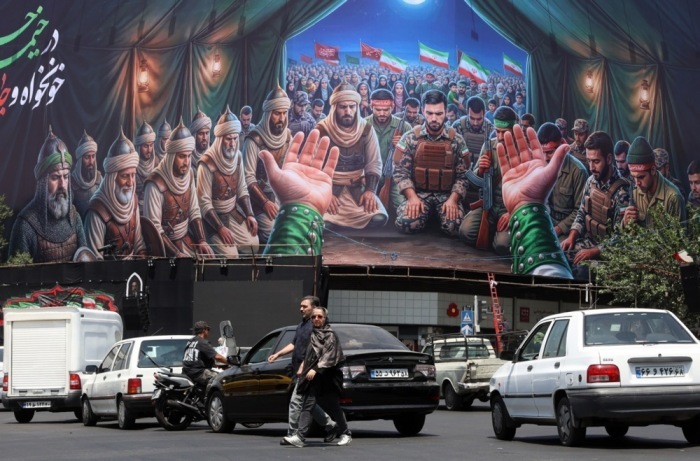 Passanten gehen am Enqelab-Platz in Teheran an einer großflächigen Werbetafel vorbei. Iran und die USA haben ein Friedensabkommen unterzeichnet. Foto: epa/Abedin Taherkenareh