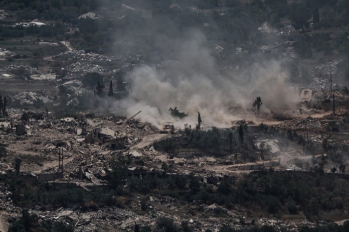 Ein israelischer Panzer manövriert nahe der Grenze zu Libanon, während ein UNIFIL-Konvoi durch das zerstörte Dorf Meiss El Jabal fährt. Foto: EPA/Atef Safadi