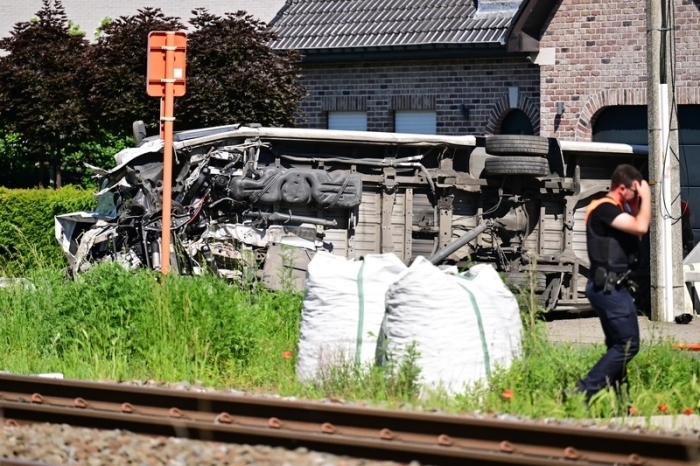 Blick auf einen umgekippten Schulbus, nachdem dieser mit einem Zug am Bahnübergang Vierhuizen in Buggenhout zusammengestoßen war. Foto: Dirk Waem/Belga/dpa