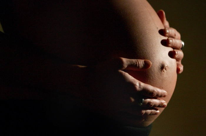 Eine hochschwangere Frau fasst sich mit beiden Händen an ihren Bauch. Foto: Felix Heyder/dpa