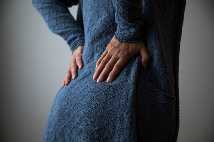 Eine Frau hält sich den unteren Rücken. Foto: Christin Klose/dpa