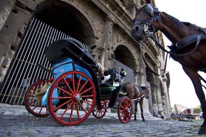Touristen sitzen auf einer Pferdekutsche vorm Kolosseum. Foto: Massimo Percossi/dpa