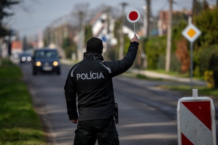 Polizisten kontrollieren ein Auto vor einem Gebäude. Archivfoto: epa/MARTIN DIVISEK