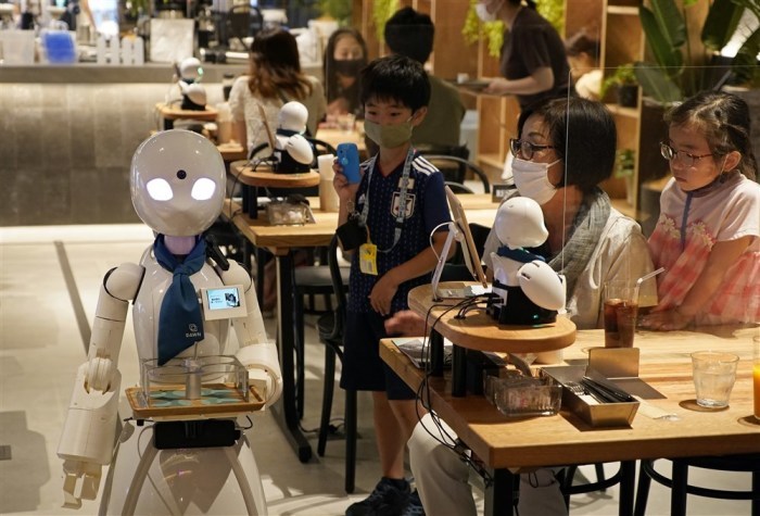 Ein OriHime-D-Roboter geht durch die Tische des Cafés 