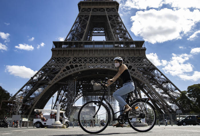 Eine Frau, die einen Gesichtsschutz trägt, fährt mit ihrem Fahrrad in der Nähe des Eiffelturms in Paris. Foto: epa/Ian Langsdon