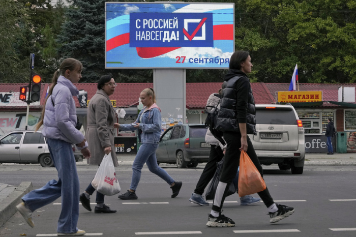 Menschen gehen an einer elektionischen Anzeige mit der Aufschrift «Für immer mit Russland» in der von Russland unterstützten und von Separatisten kontrollierten Volksrepublik Luhansk vorbei. Foto: Uncredited/Ap/dpa