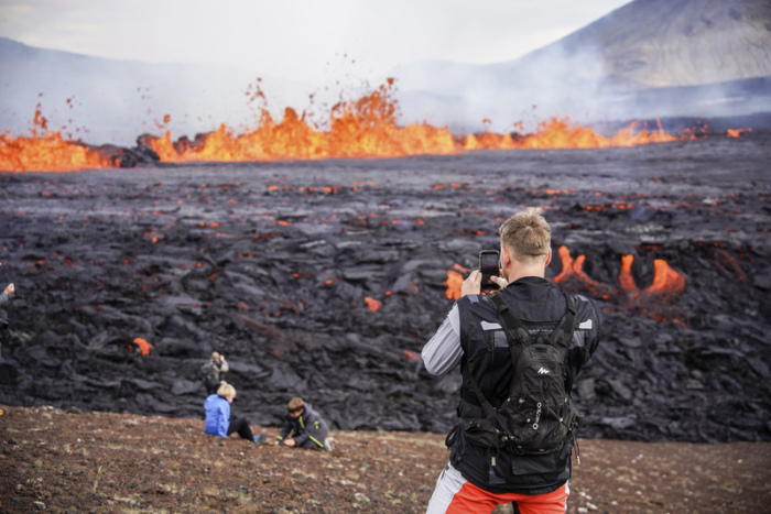 Ein Mann macht am Vulkan Fagradalsfjall Aufnahmen von ausgetretener Lava mit seinem Smartphone. Foto: Marco Di Marco