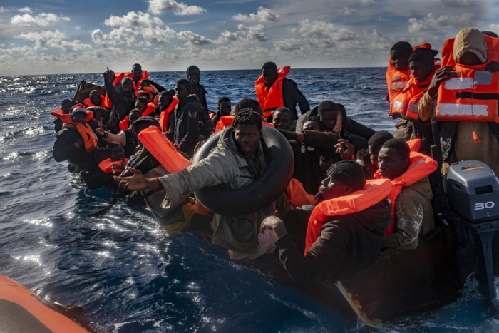 Mehrere Migranten sitzen in einem Boot im Mittelmeer, während Rettungskräfte versuchen ihnen zu helfen. Foto: Antonio Sempere/Europa Press/dpa