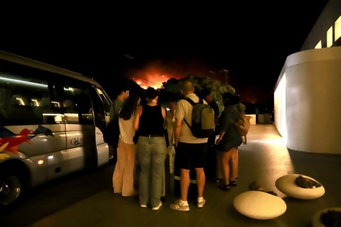Touristen verlassen ein Hotel während eines großflächigen Waldbrands nahe Ierapetra auf der griechischen Insel Kreta. Foto: epa/Nikos Chalkiadakis