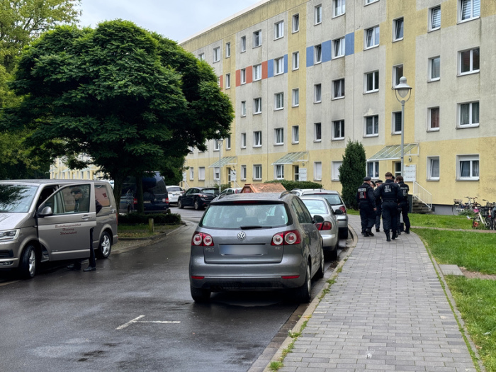 Polizisten und ein Fahrzeug eines Bestattungsunternehmen stehen in der Nähe des Einsatzorts, der möglichwerweise im Zusammenhang mit der Attacke in Wolmirstedt steht. Foto: Thomas Schulz/dpa