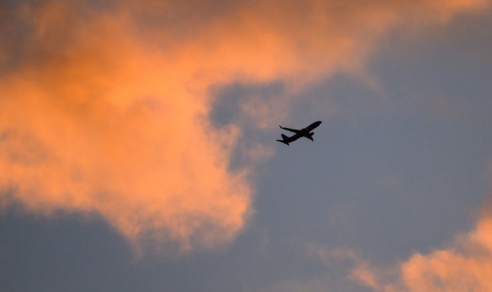 Eine Boeing 737 von TUI fly auf dem Weg von Hannover nach Palma de Mallorca zeichnet sich vor dem vom Sonnenaufgang verfärbten Morgenhimmel ab. Foto: Julian Stratenschulte/dpa