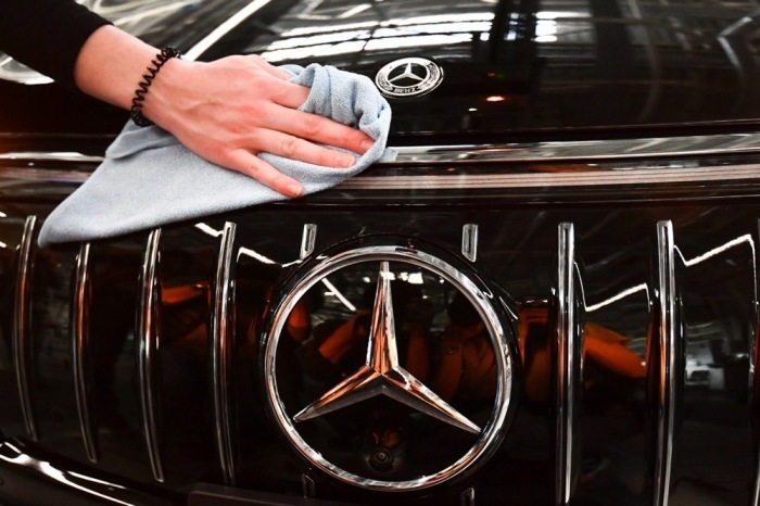 Mercedes Mitarbeiter reinigt das Logo auf einem EQS Auto im Mercedes-Benz Werk Sindelfingen. Foto: epa/Anna Szilagyi