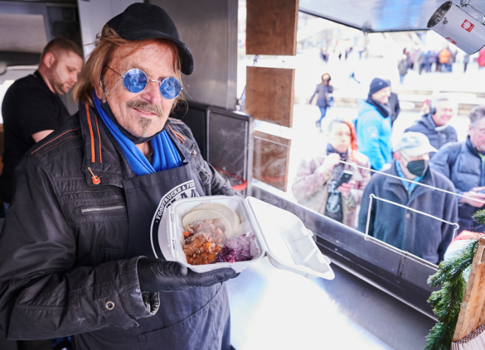 Frank Zander steht im Caritas-Foodtruck und verteilt warme Mahlzeiten an Obdachlose und bedürftige Menschen auf dem Alexanderplatz. Foto: Annette Riedl/dpa