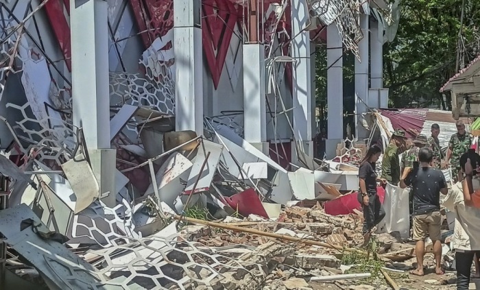Menschen begutachten Gebäudeschäden nach starkem Erdbeben in Sulawesi. Behörden warnen vor Tsunami, Rettungskräfte sind im Einsatz. Foto: epa/Basarnas / Handout