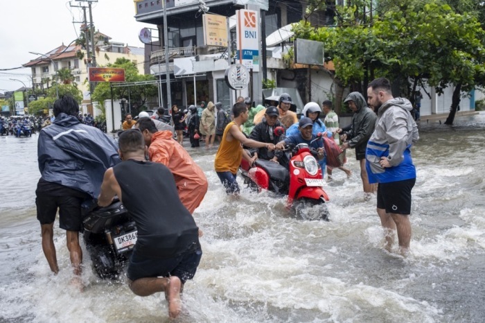 Nach tagelangen Regenfällen stehen Straßen im beliebten Urlaubsort Kuta unter Wasser. Anwohner und Touristen waten durch überflutete Gassen. Foto: epa/Made Nagi